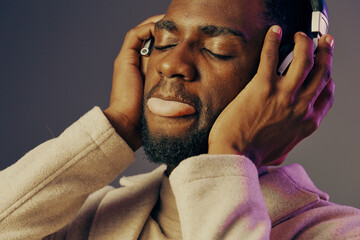 A young Black man enjoying music with headphones, expressing deep emotion and relaxation, creating...