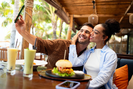 Young couple sharing dining experience at tropical restaurant, engaging with their online followers - Powered by Adobe