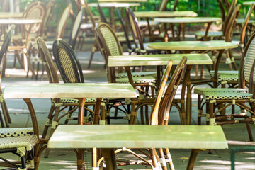 Outdoor cafe terrace with empty tables and chairs in sunlit setting