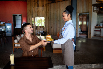 Waitress delivers a juicy burger in cozy restaurant setting with a warm smile and great hospitality