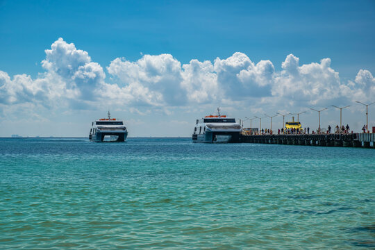 Tourist ferries to Cozumel Island docked at Playa del Carmen city pier, awaiting passengers to board, sunny day, blue sky. South destination, travel concept.