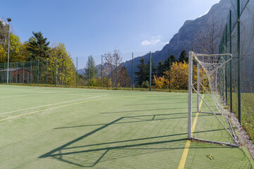 Football field with forest and mountain in back, Alps, Italy