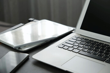Modern workspace with laptop, tablet, and smartphone on dark desk, reflecting clean and minimalistic tech setup for productivity and communication