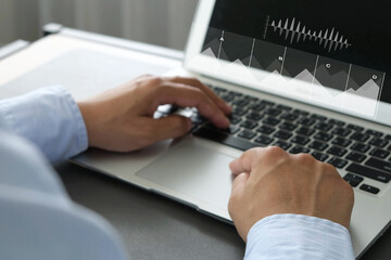 Businessman typing on laptop keyboard with data visualization charts overlayed, representing work, business analysis, economy, and digital productivity in modern office environment