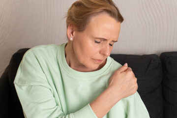 Close-up of woman holding shoulder in pain, suffering from joint discomfort or muscle tension. Concept of arthritis, physical health, body awareness, injury and pain relief.