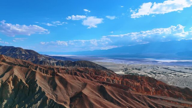 Bright hot sun dazzles the barren desert among the mountain ranges. Drone flight over the Death Valley National Park, California, USA.