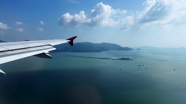 Airplane wing overlooking islands and a coastal bridge