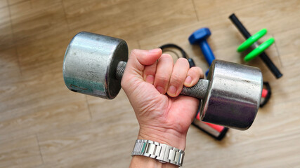 Close-up of a hand gripping a heavy dumbbell during a workout. Strength training and fitness exercise session at home or gym. Concept of determination, power, and healthy lifestyle.
