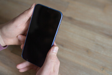 Hands holding a smartphone with a blank screen, showcasing the device's sleek design and modern aesthetics, ideal for mockup presentations and digital design projects