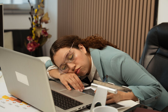 Young woman sleeping at office desk exhausted from work