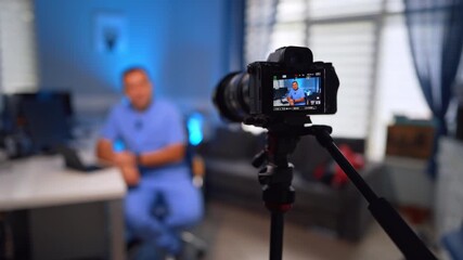 Modern professional camera set in front of the man sitting at desk. Selective focus on a doctor recording video vlog. - Powered by Adobe