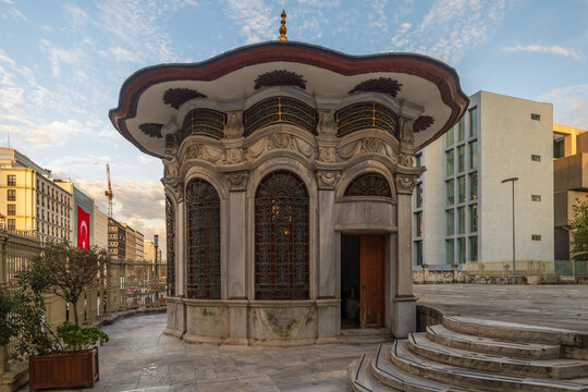 Ornate marble fountain (sebil) in Istanbul surrounded by contrasting modern architecture at dusk