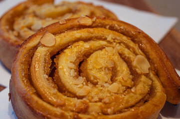 Close-up of a sweet cinnamon  sticky bun, filled with a layer of caramel sauce and almond nuts.
