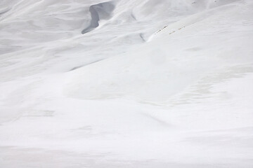 Trekkers hike along the snowy road towards Annapurna Base Camp in the Himalayas, Nepal. The landscape is completely covered in a thick layer of fresh white snow