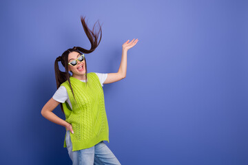 Young woman in a bright lime vest and white shirt poses joyfully against a blue background for...