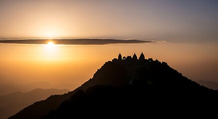 Silhouette of temples on a mountain peak at sunset with hazy layers of mountains image photo