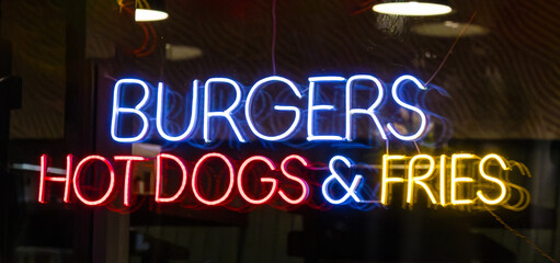 Colorful glowing neon signs food adverts during night in urban city street 