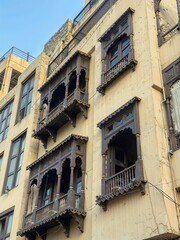 vintage building facade with traditional wooden balconies and ornate carved windows under clear blue sky, historical architecture design in old city

