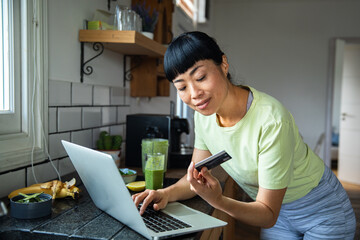Young adult woman shopping online in kitchen