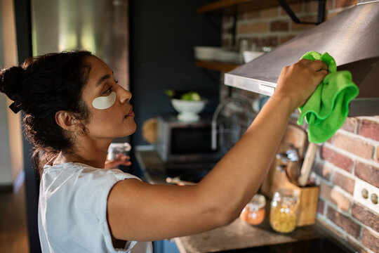 Young woman cleaning kitchen at home