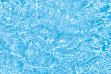 Blue water with ripples on the surface. Defocus blurred transparent blue colored clear calm water surface texture with splashes and bubbles. Water waves with shining pattern texture background.