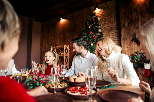 Family celebration at a Christmas dinner around a festive table with a decorated tree and warm cozy ambiance in a modern home