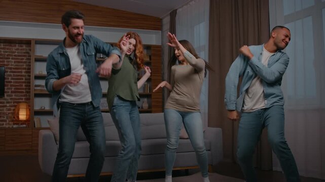 Happy four multiethnic friends men women dancing humorous leisure at home party ethnic diversity roommates move dance fun joy enjoying music audio stereo sound neighbors together celebrate moving day