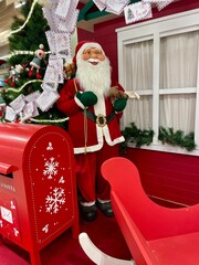 Life-size Santa Claus figure with Christmas mailbox and letters to Santa, festive holiday decoration.