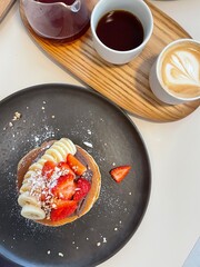 Pancakes and cup of coffee on a wooden table, cozy breakfast scene with warm morning light