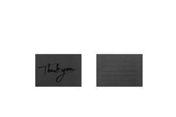 A black card with black handwritten Thank you and ruled lines, photographed from overhead.	
