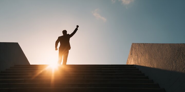 Man is standing on a set of stairs and is raising his fist in the air