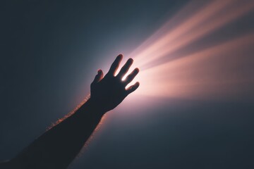 Silhouette of a hand reaching toward a glowing light, symbolizing ambition, hope, and aspiration.