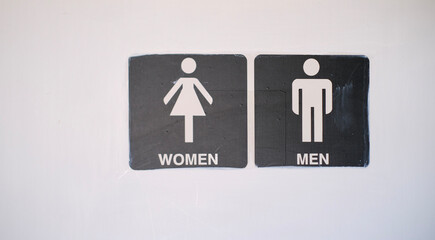 Restroom door signs with minimalist women and men icons on a white wall.