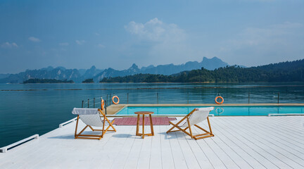 wooden beach chair and coffee table on white raft and swimming pool at waterfront of the open water in natural lake