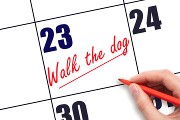 23 rd day of the month.  Hand writing Walk the dog reminder and drawing a line on calendar with red...