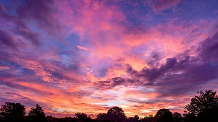 A beautiful sunset with a pink and purple sky. The sky is filled with clouds and the sun is setting
