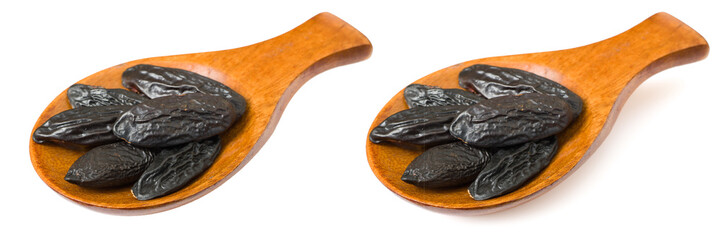 Tonka beans in the wooden spoon, isolated on white background.