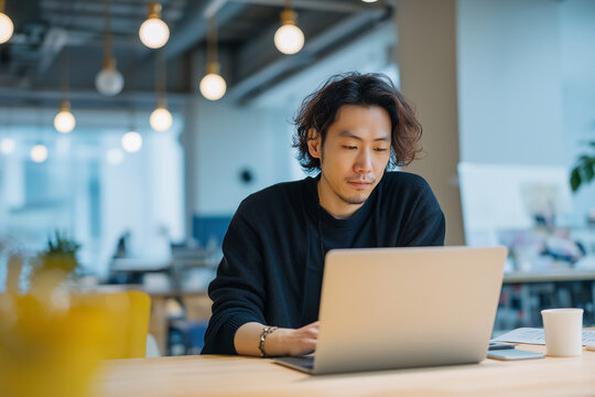 オフィスでノートパソコンを使って仕事をする若い男性