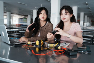 Asian female students and their teenage friends in high school chat and work together on homework to build a robot in the school cafeteria.