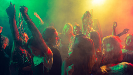 New Year party illuminated by green and amber light with cheerful movement. Concept of entertainment visuals, emotional nightlife, event celebration, and youth culture