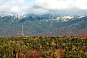 Autumn scene in White Mountains of New Hampshire. Tracks of cog railway climbing towards snow covered summit of Mount Washington.