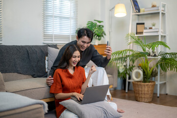 Asian couple celebrating online success with laptop at home