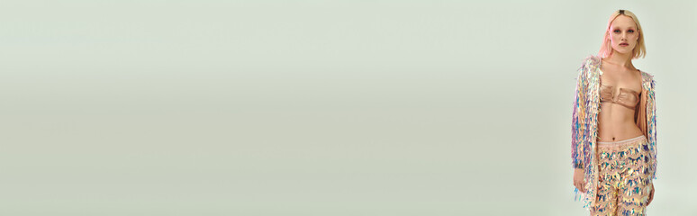 Blonde young woman shines in holographic party outfit while posing in studio setting