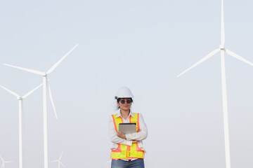 A female engineer in safety gear stands confidently among wind turbines, showcasing a commitment to sustainable energy solutions.