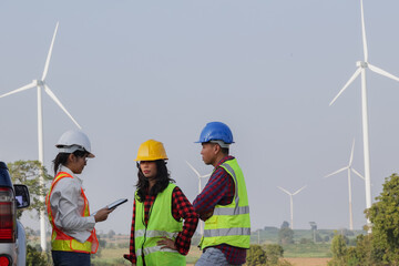 Engineers discuss plans at a wind farm site, showcasing teamwork and renewable energy in action for...