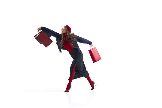 Fashion woman in red and navy outfit walking gracefully with shopping bags in motion. Concept of elegant lifestyle, retail energy, modern fashion expression for editorial and advertising use.