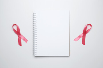 Pink ribbon on notebook mockup for breast cancer awareness and prevention reminders