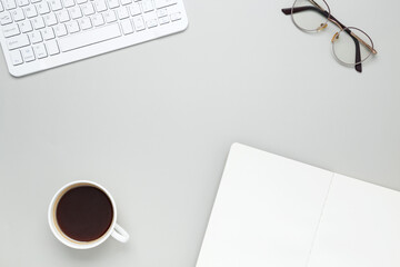 Cozy workspace with coffee cup, keyboard, glasses and notebook creating focused morning atmosphere