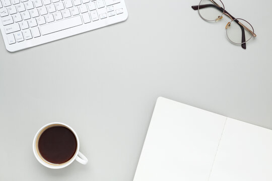 Cozy workspace with coffee cup, keyboard, glasses and notebook creating focused morning atmosphere