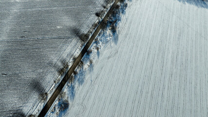Aerial View of Long Empty Road Through Snowy Winter Fields and Bare Trees. Peaceful Rural Landscape, Seasonal Nature Background, Travel and Countryside Concept